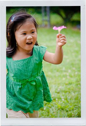 Photograph: A preschool-aged girl runs across a grass field with a pink flower in her hand. (Photograph by Alex Lazara)