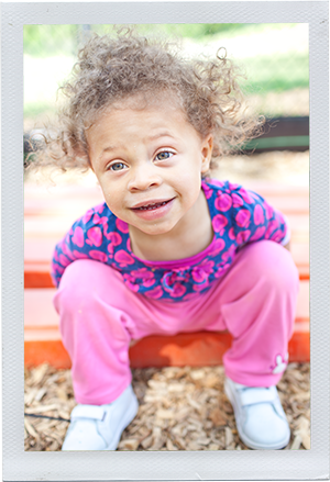 Photograph: A female toddler leans over and smiles at the camera. (Photograph by Alex Lazara)